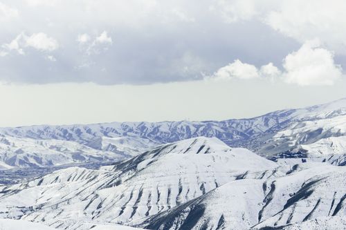 Free Majestic snow-covered mountains stretch under a cloudy sky, capturing nature's serene beauty. Stock Photo