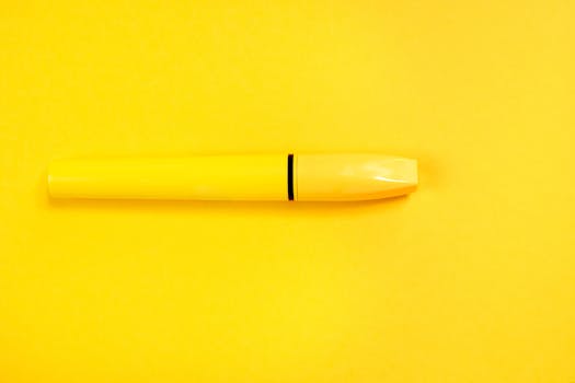 Close-up of a yellow mascara tube against a vibrant yellow background, ideal for beauty themes.