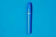 明亮的蓝色睫毛膏管平放在配套的蓝色背景上，非常适合美容主题