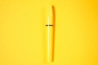 极简主义的黄色睫毛膏管在充满活力的黄色背景上展示