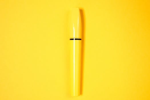 极简主义的黄色睫毛膏管在充满活力的黄色背景上展示