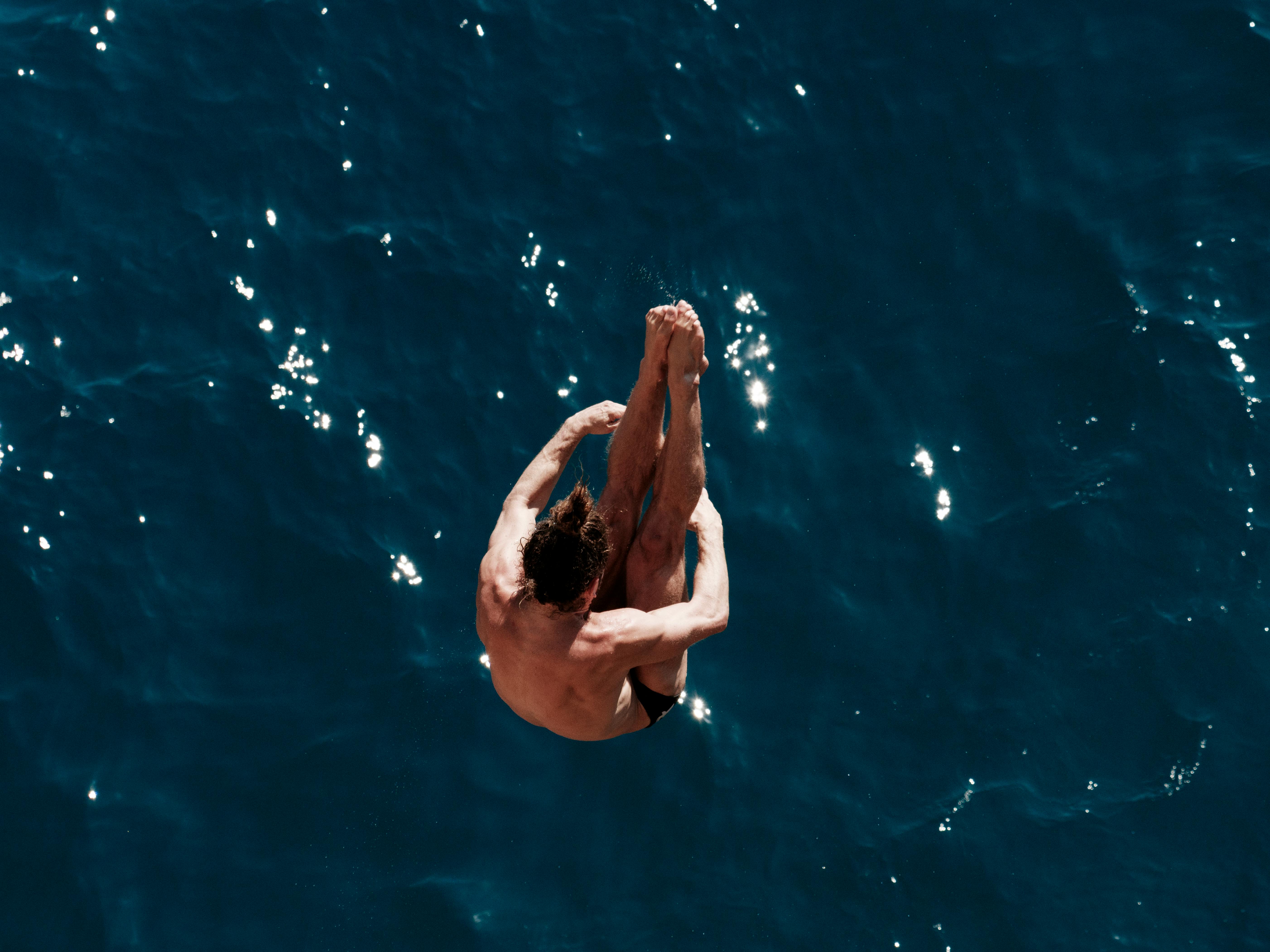 A man elegantly dives into the vibrant blue waters of the Aegean Sea, showcasing the thrill of summer sports.