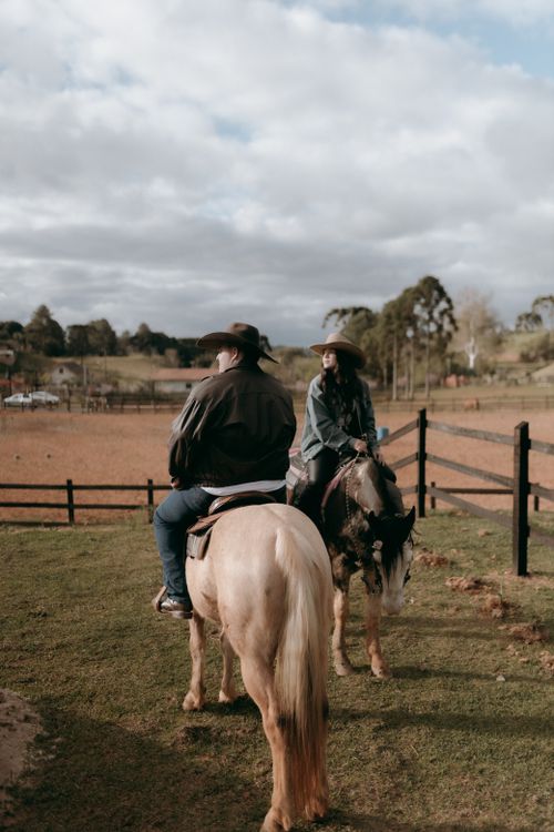 Free Two riders on horses in a scenic rural landscape with a wooden fence. Stock Photo