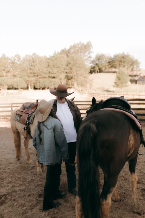 Free Two cowboys with horses in a rustic outdoor setting, wearing hats and denim jackets. Stock Photo
