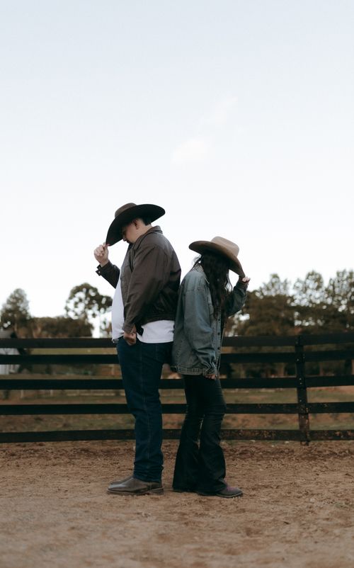 Free Two cowboys standing back-to-back in a rural setting, evoking a western theme. Stock Photo