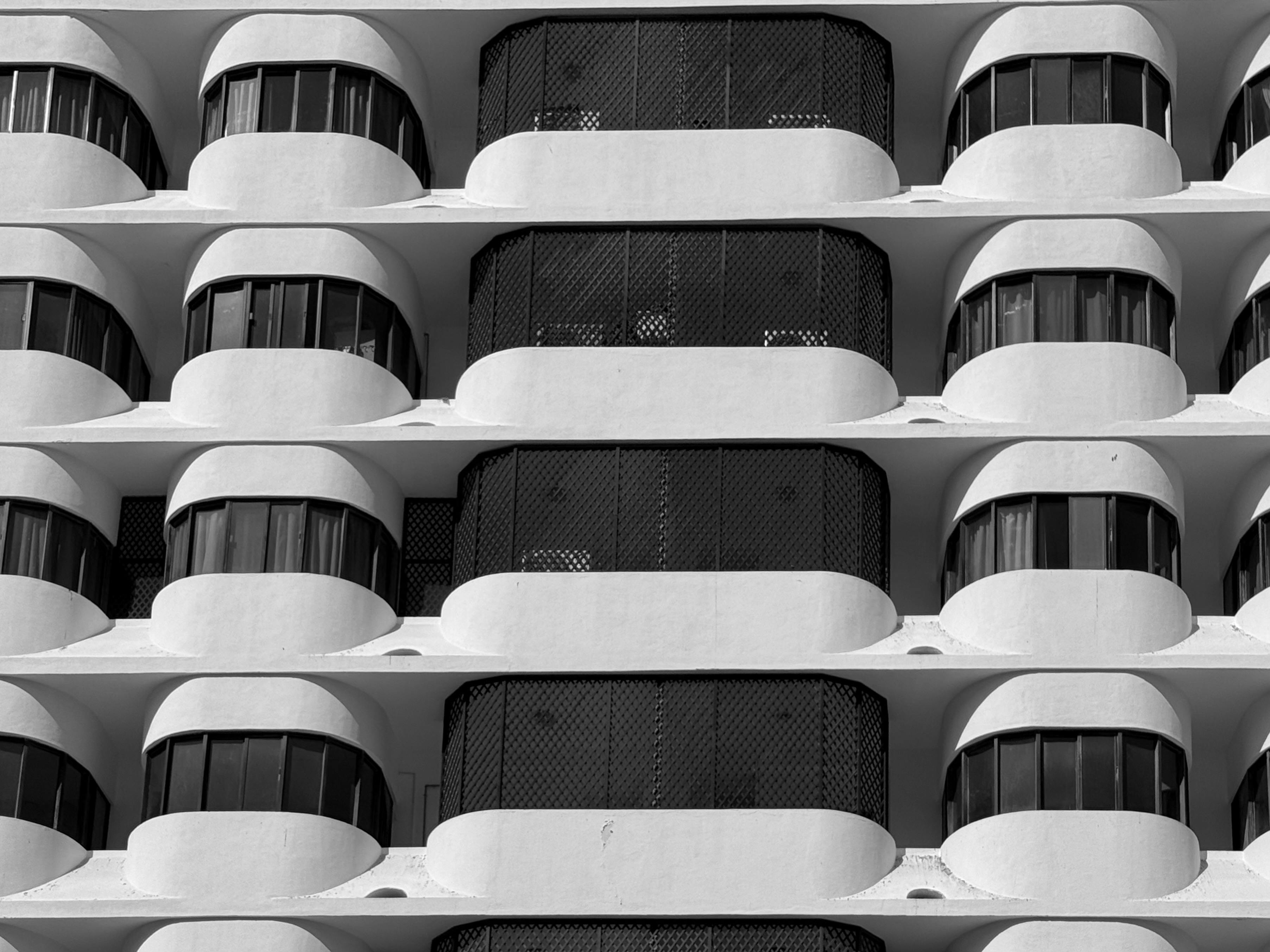 Gratuit O fotografie minimalistă alb-negru care surprinde balcoane curbate repetitive ale unei clădiri moderne. Fotografie de stoc