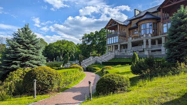 Stunning wooden manor surrounded by well-manicured gardens and vibrant trees under a clear blue sky.