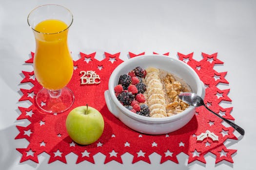 A vibrant Christmas breakfast featuring muesli, fruit, apple, and orange juice on a festive mat.
