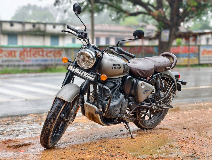 Royal Enfield motorcycle parked on a rainy street in India.