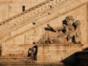 日落时分，一对夫妇在罗马的一座历史雕像旁共度浪漫时刻