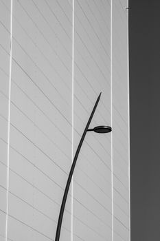 Black and white minimalist photo of a modern street lamp against a building.