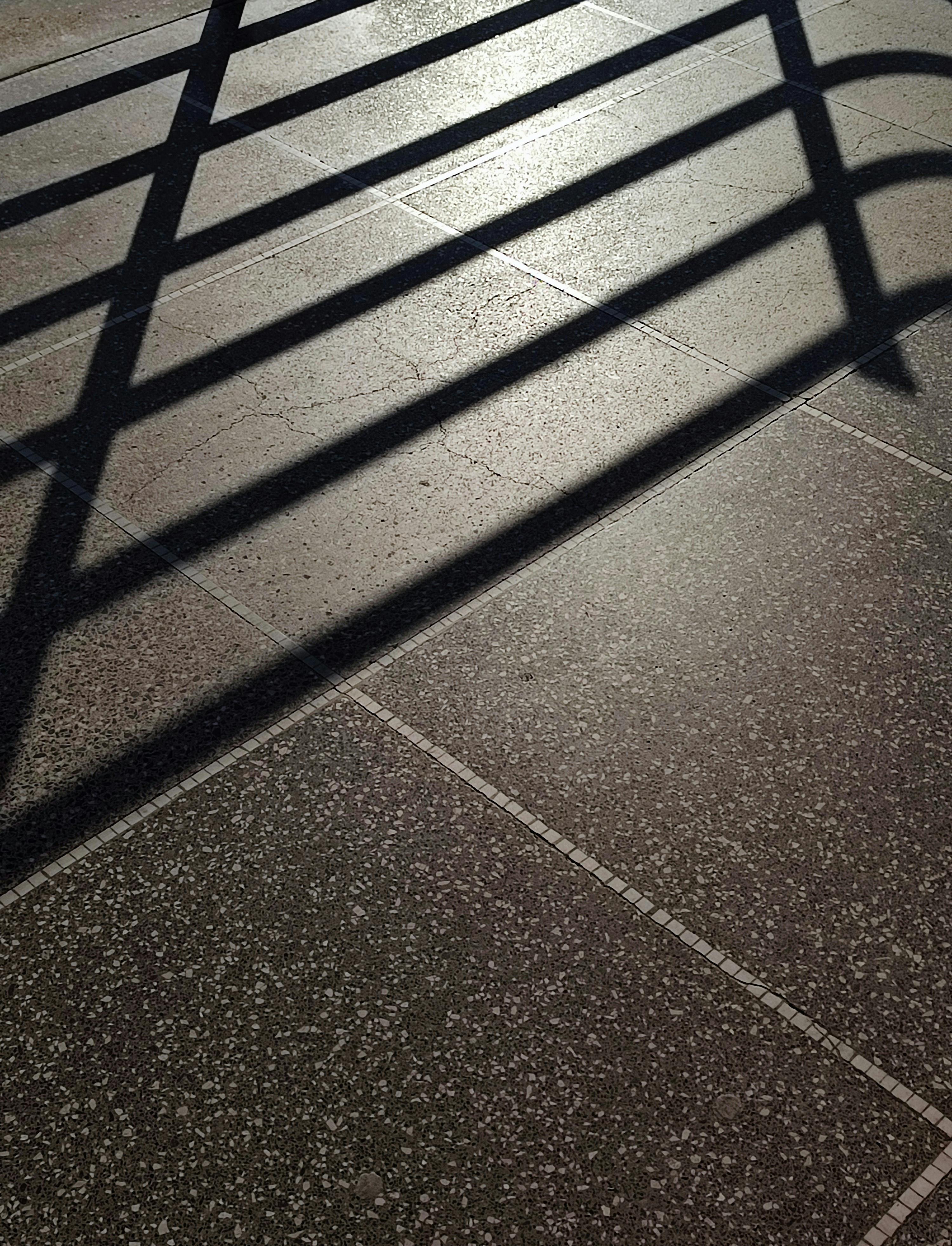 grátis Sombras geométricas projetadas em um pavimento texturizado criam um padrão abstrato. Foto profissional