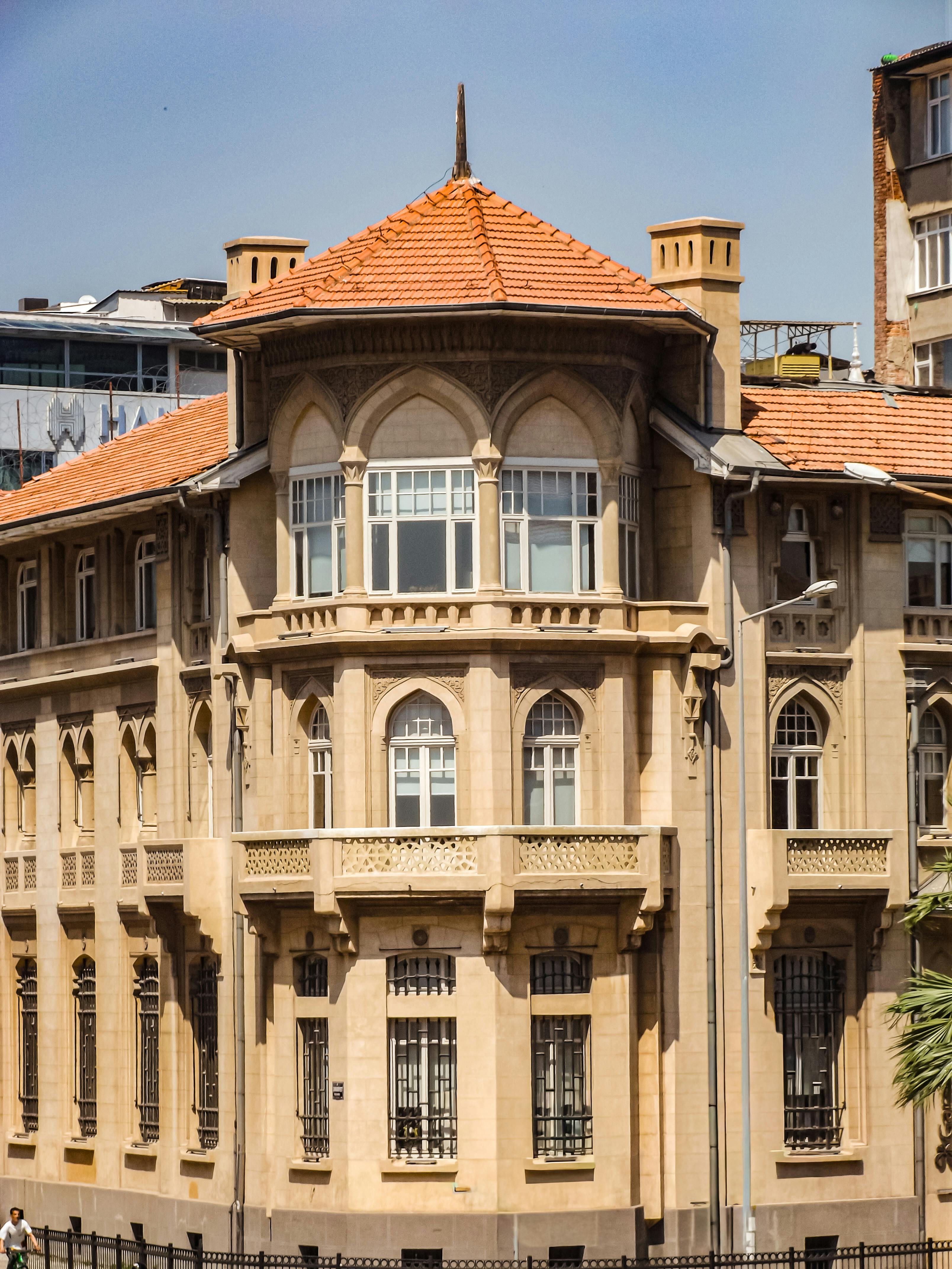 Elegant historic building with ornate architecture and an orange roof on a sunny day.