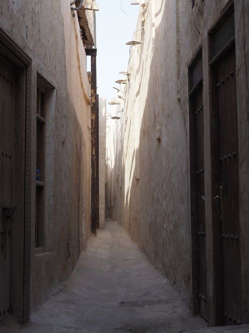 Free A serene narrow alleyway in the traditional Souk of Doha, Qatar, casting dramatic afternoon shadows. Stock Photo