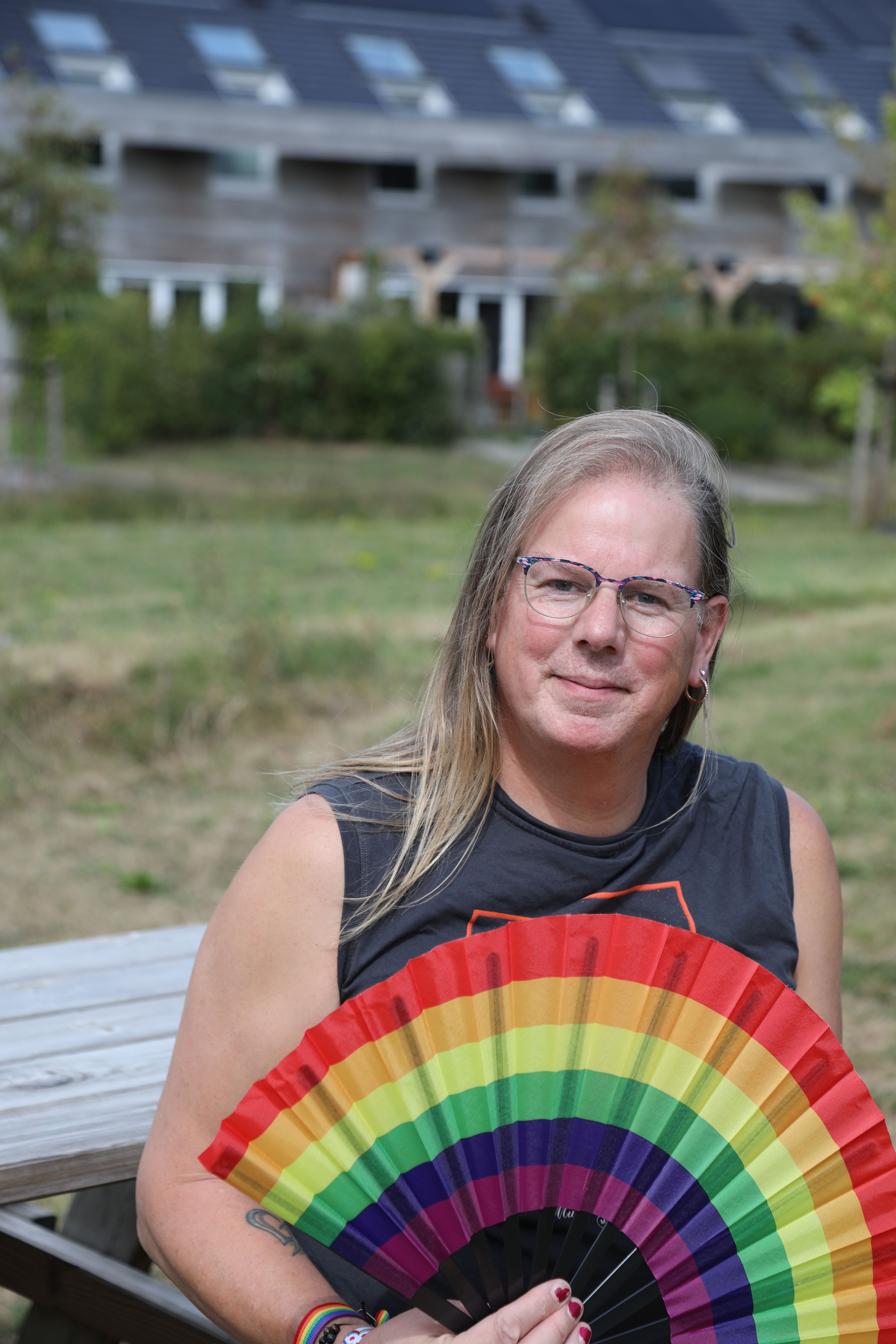Person holding a rainbow fan outdoors, showing support for LGBTQ pride.