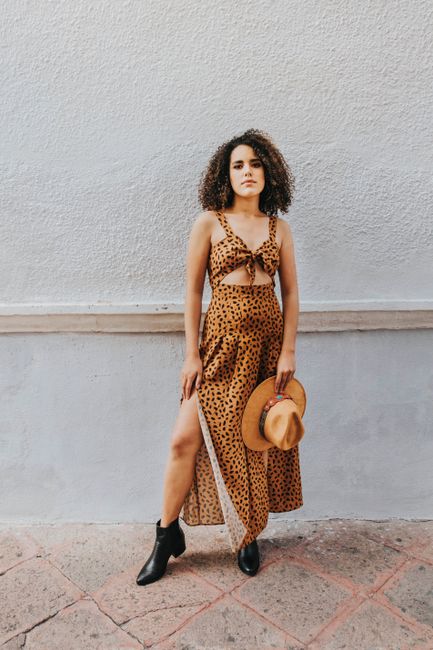 Elegant woman in a leopard print dress posing outdoors. Modern and stylish fashion.
