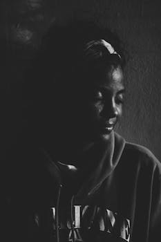 这幅黑白肖像画描绘了一位闭着眼睛、身穿连帽衫的孤独女子