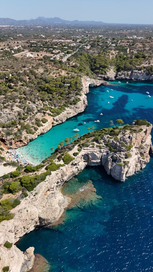 Free A breathtaking aerial shot of a Mediterranean coastline with clear blue waters, cliffs, and boats. Stock Photo