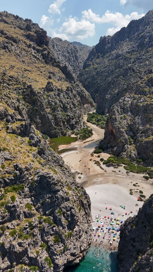 Free Stunning aerial view of a hidden beach nestled between rocky cliffs under a blue sky. Stock Photo