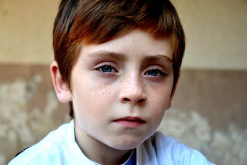 Free Close-up portrait of a young boy with freckles, expressing calmness and thoughtfulness. Stock Photo