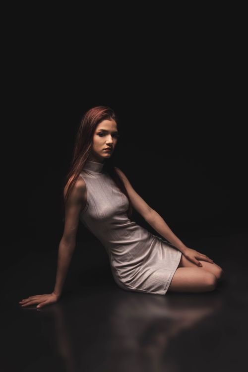 Free Graceful female poses in chic dress against a dark backdrop, exuding elegance and style. Stock Photo