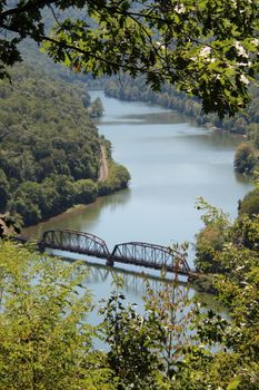 Discover a peaceful river scene with an iron bridge and dense forests.