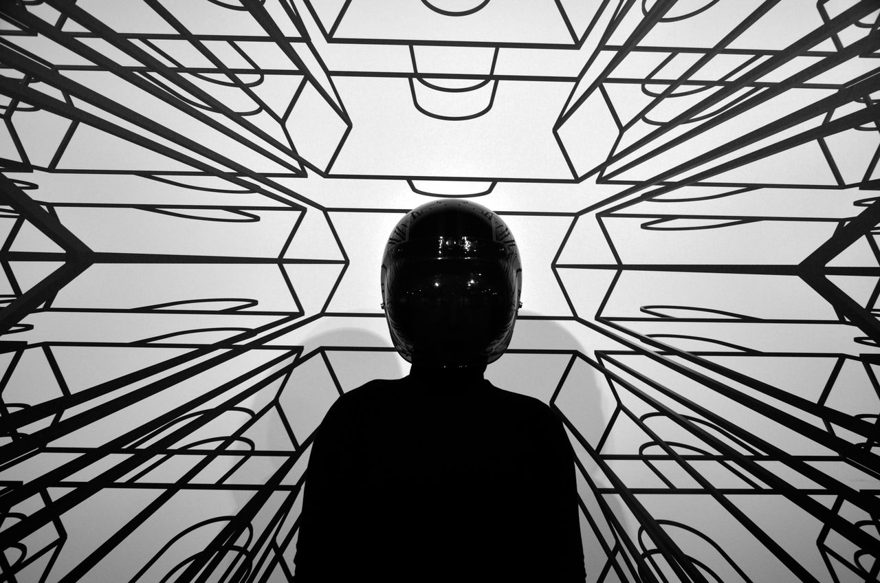a person wearing a helmet stands silhouetted against a geometric black