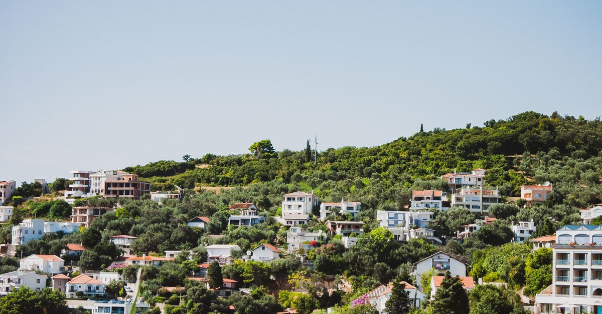 Picturesque hillside houses with lush greenery in a Mediterranean coastal location.