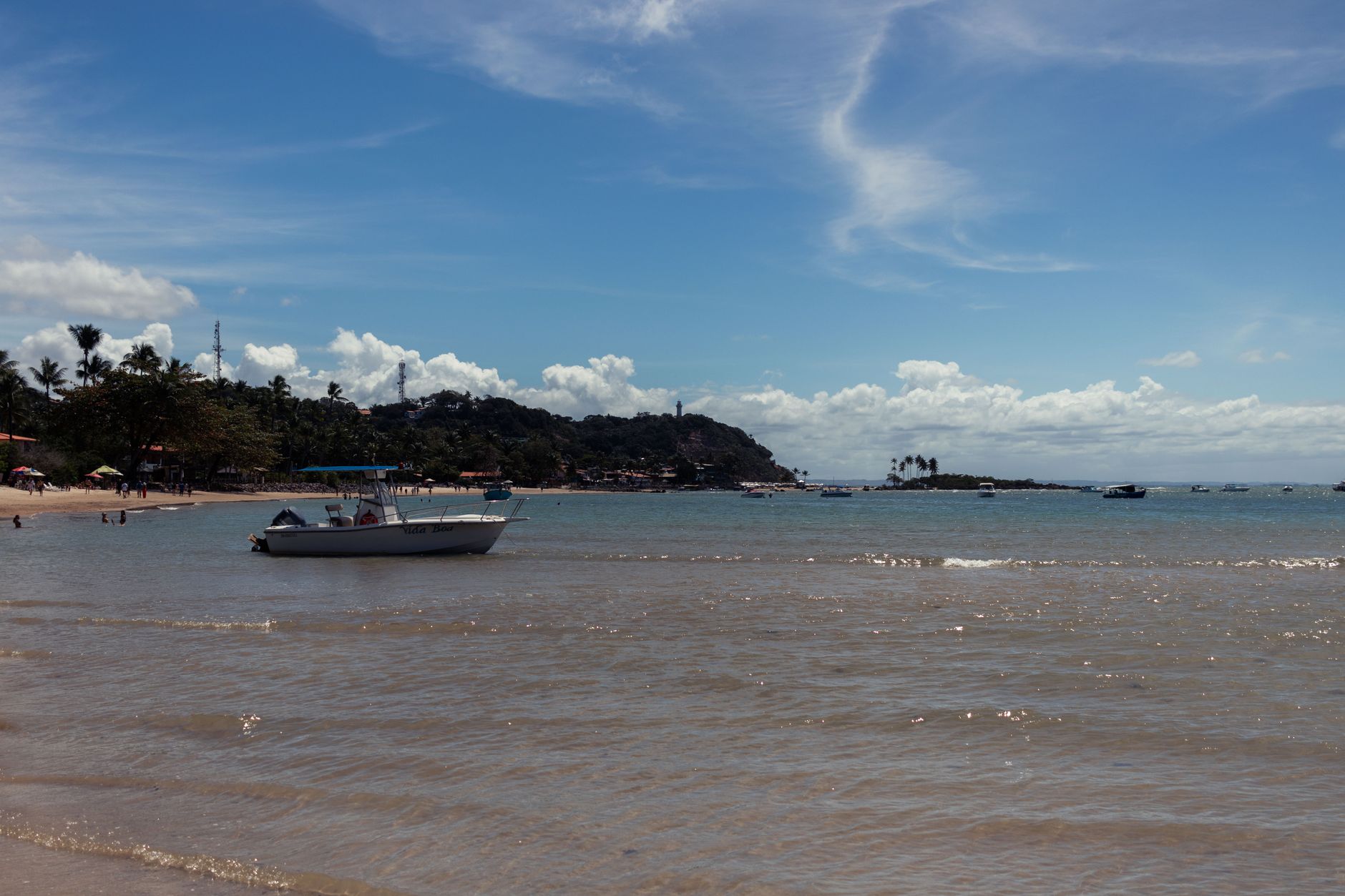 Picturesque view of a boat on the clear waters of Morro de São Paulo beach under a vibrant blue sky.