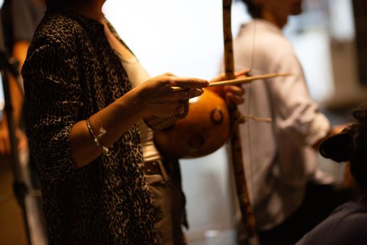 Detailed view of hands playing a berimbau, a traditional Brazilian instrument, in a performance setting.