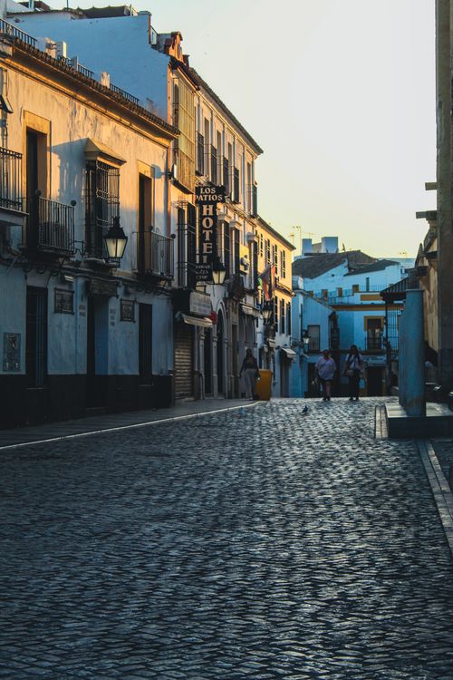 Free Cobblestone street and historic architecture in Córdoba at sunset, with people enjoying a leisurely walk. Stock Photo