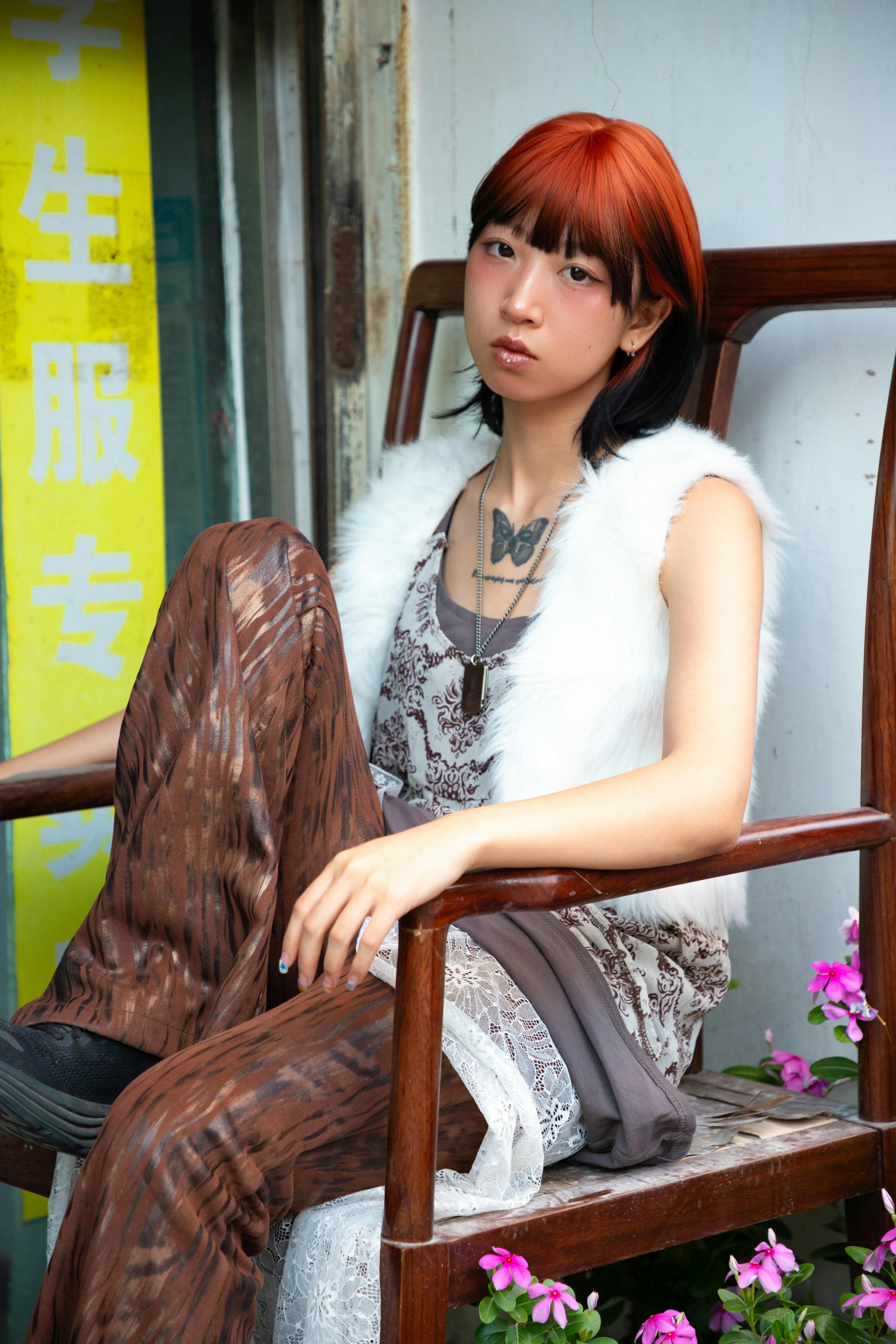 Gratis Portrett av en ung voksen med dristig hår og moteriktig stil, sittende avslappet utendørs. Arkivbilde