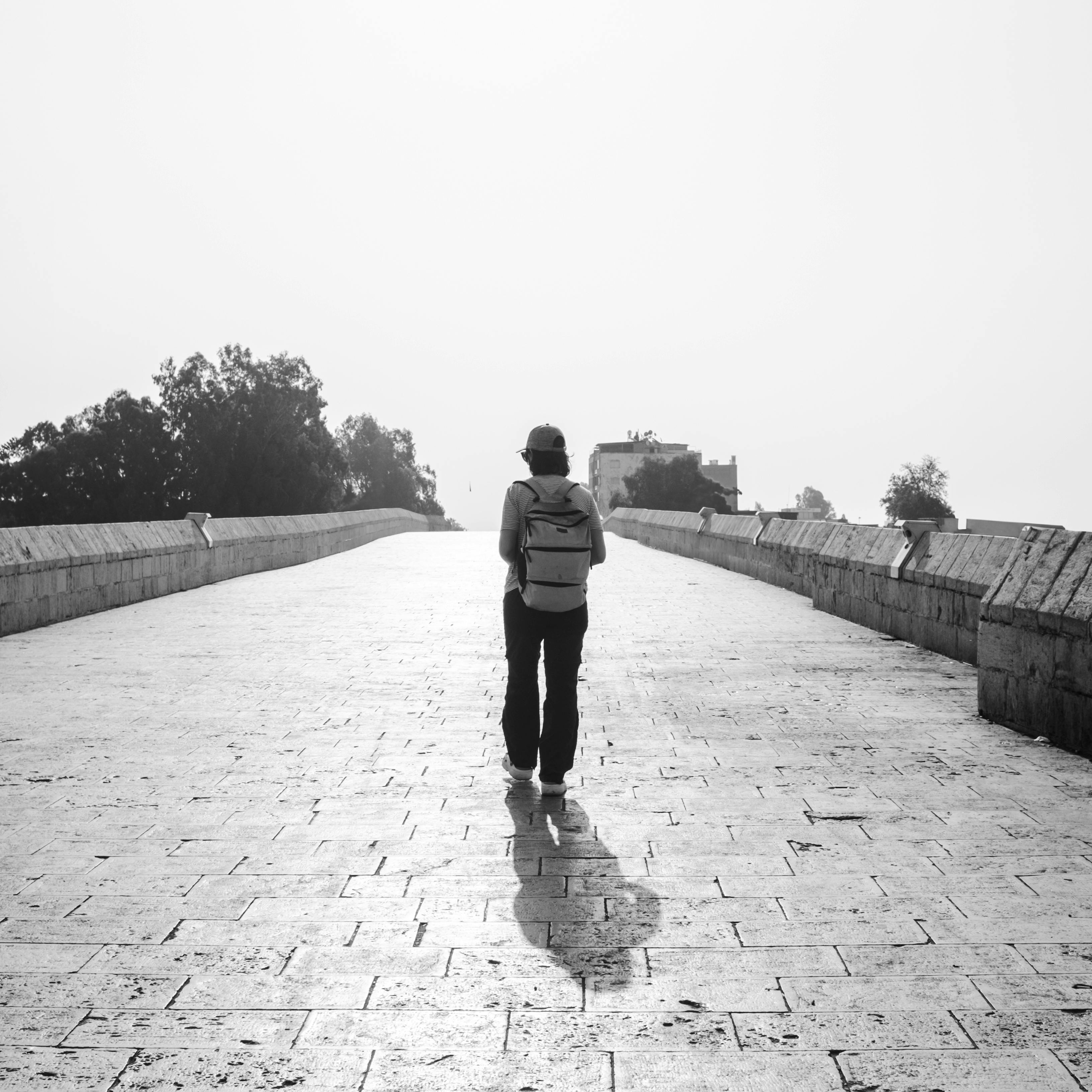Lone Traveler on Empty Bridge in Black and White