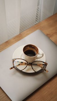 A stylish setup with coffee, glasses, and laptop for a workday boost indoors.