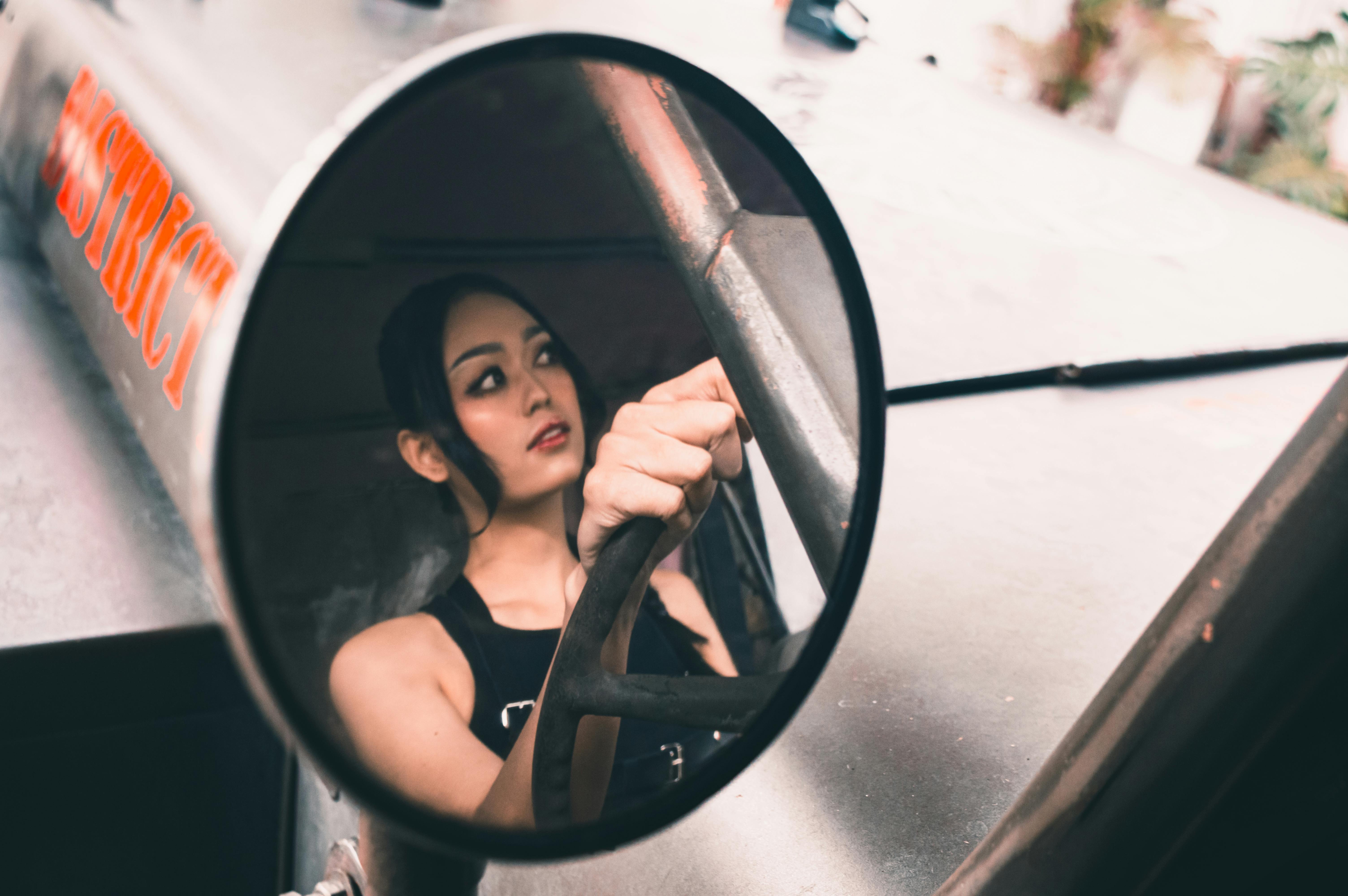 Free Artistic shot capturing a woman in a vehicle mirror reflection, focusing on driving. Stock Photo