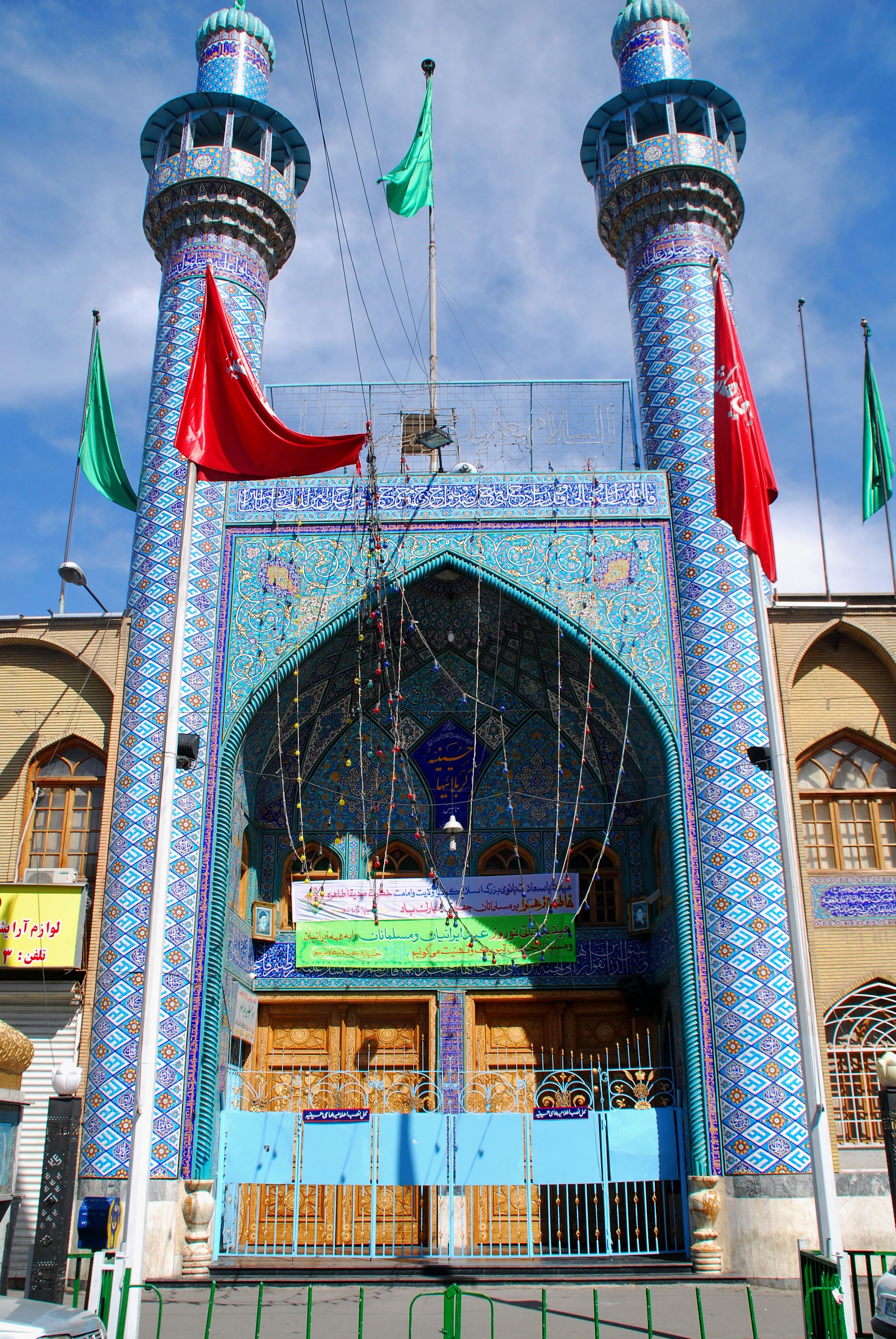 Vibrant blue-tiled mosque with minarets in Tehran, showcasing Islamic architecture.