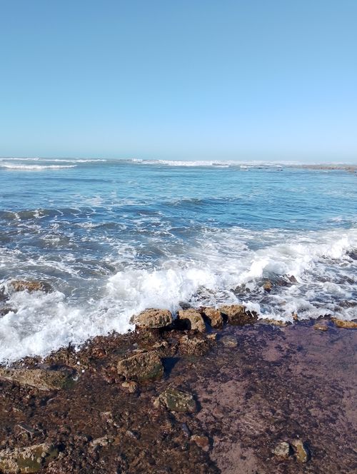 Free Peaceful ocean waves crashing on rocky Casablanca shore under clear skies. Stock Photo