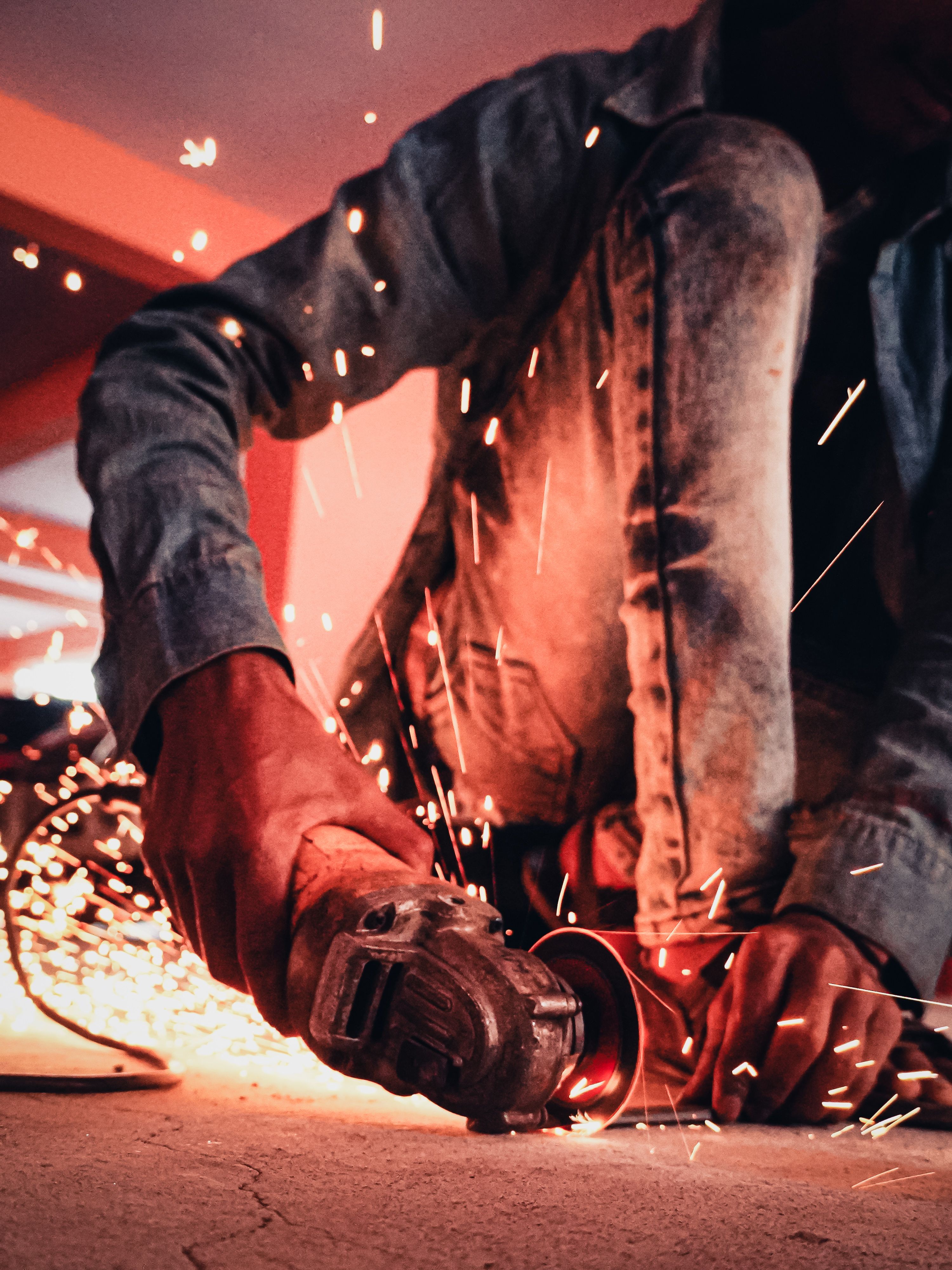 Close-up of a worker using an angle grinder, creating sparks in an industrial setting.