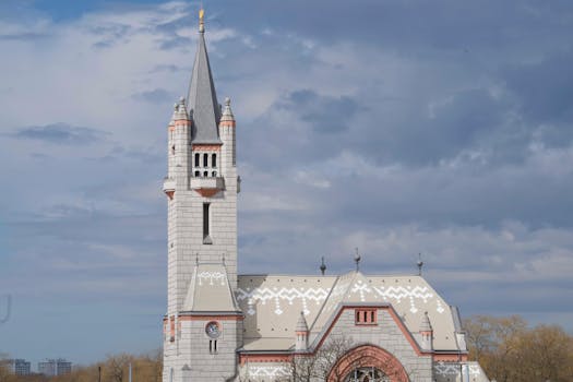 Stunning Gothic Revival church with intricate architecture and ornate tower against a dramatic sky.
