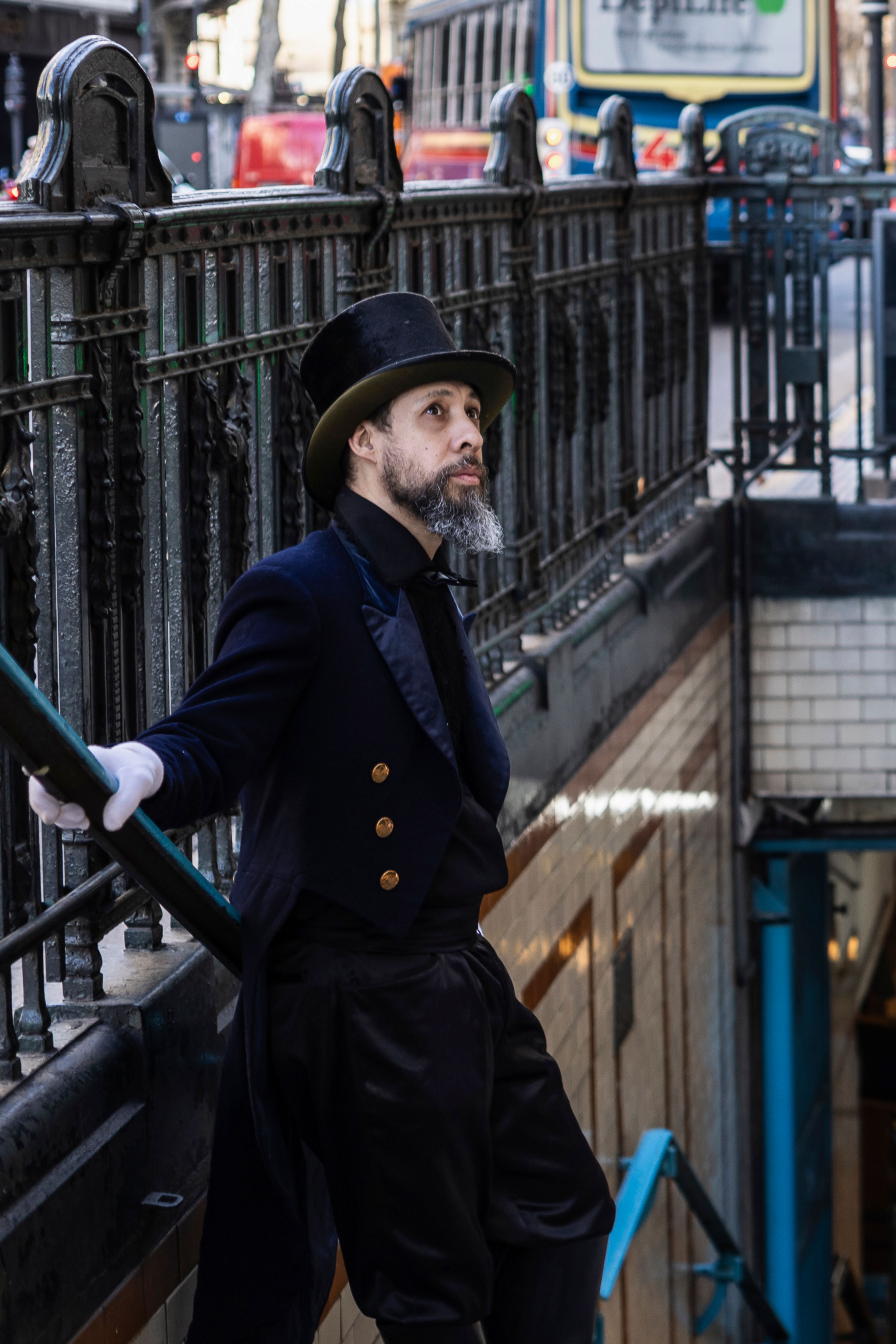 Elegant man in top hat and coat leans on railing, reflecting in Buenos Aires street.