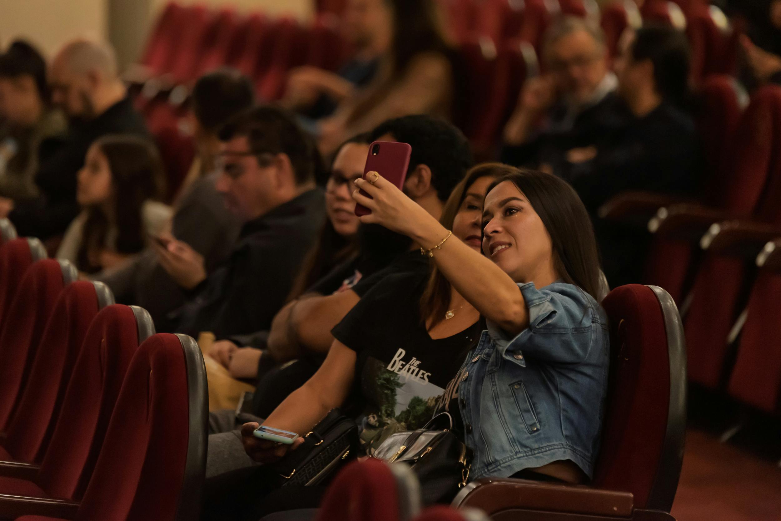 Ücretsiz Bir tiyatroda bulunan yetişkinlerden oluşan grup, seyircilerin arasında selfie çeken iki kadına odaklanıyor. Stok Fotoğraflar