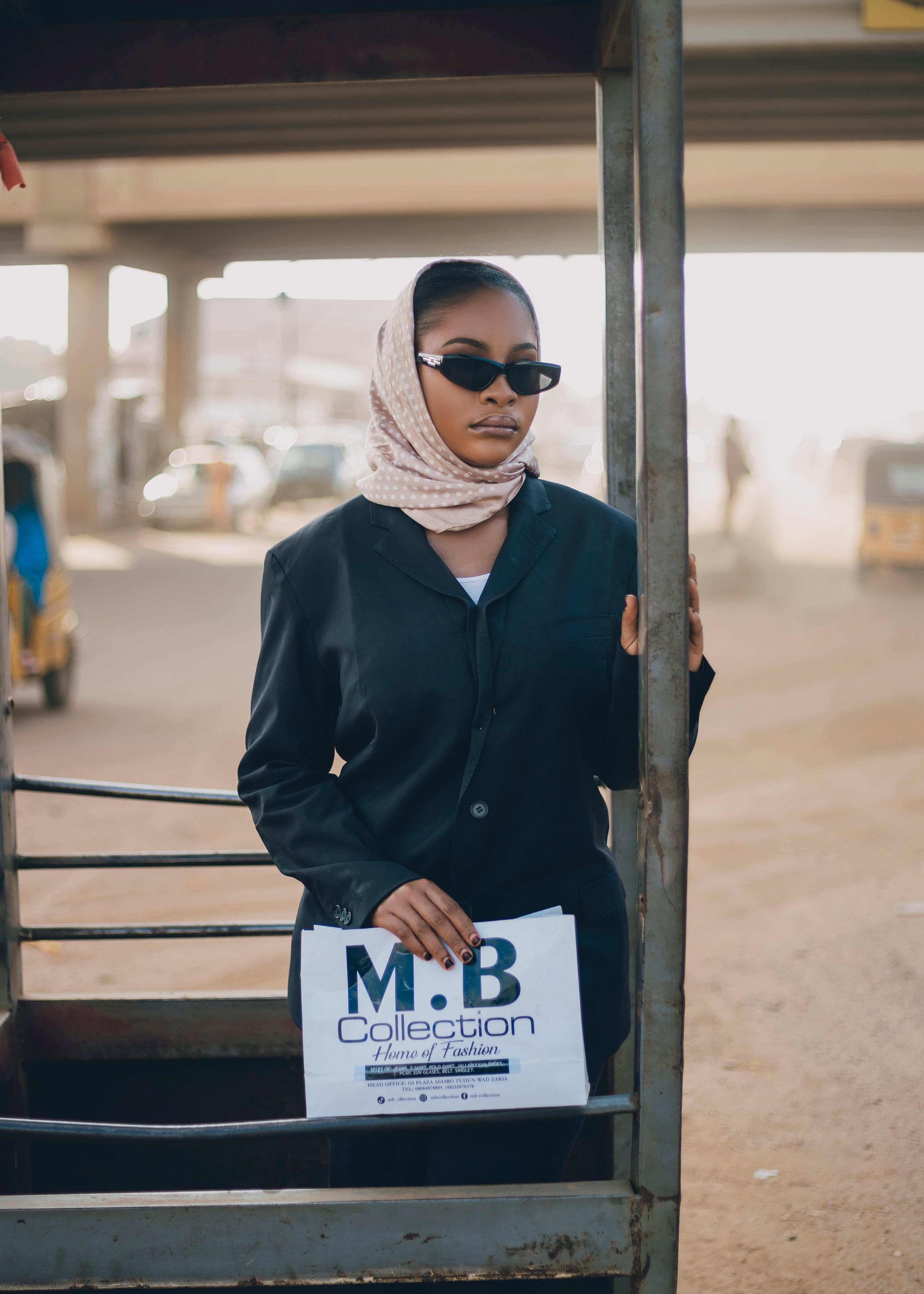 Stylish woman in sunglasses and scarf at urban location. Fashion and style.