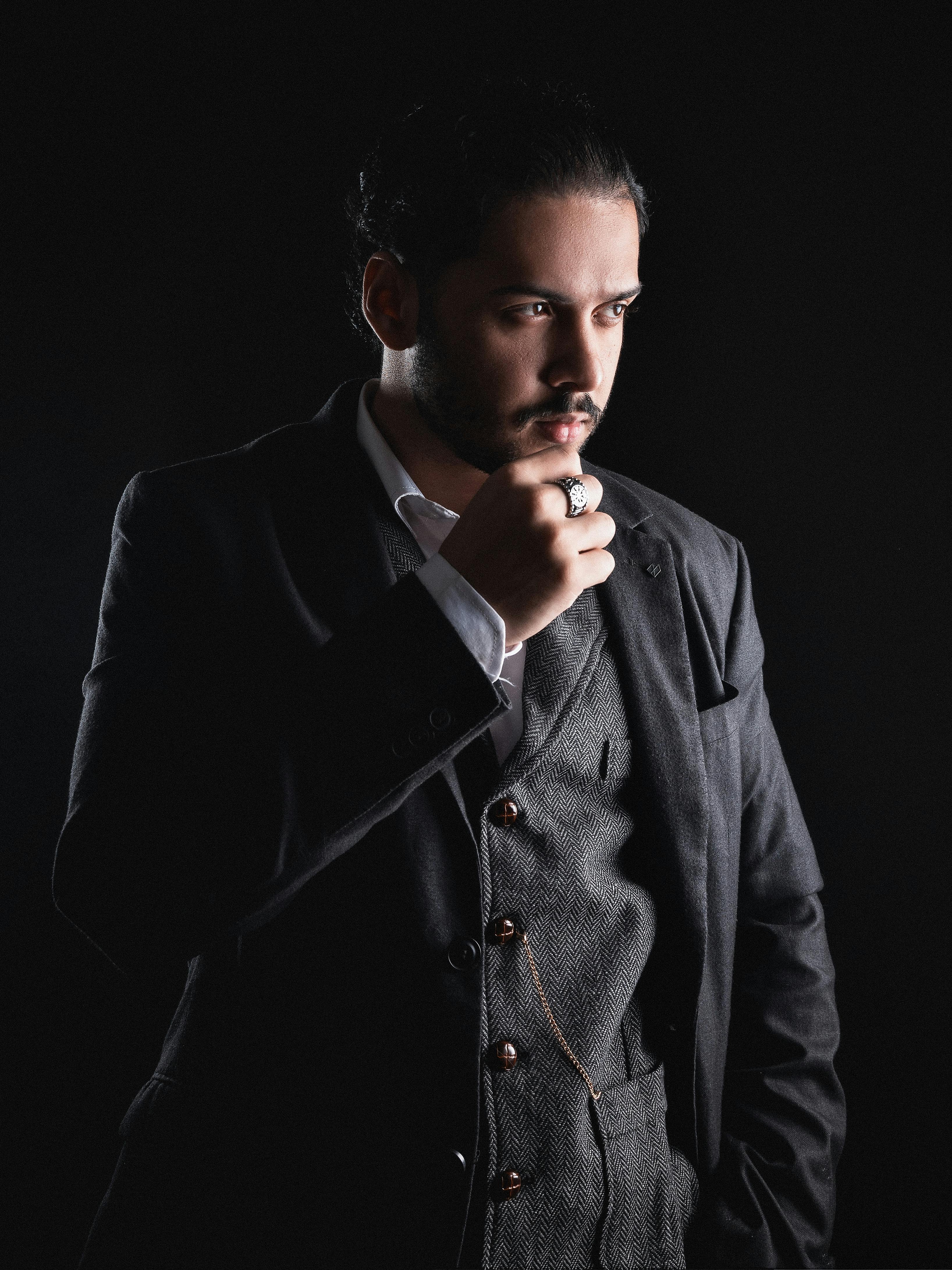 Gratuit Un homme pensif dans un costume sombre et un gilet regardant de manière introspective sur un fond sombre. Photos