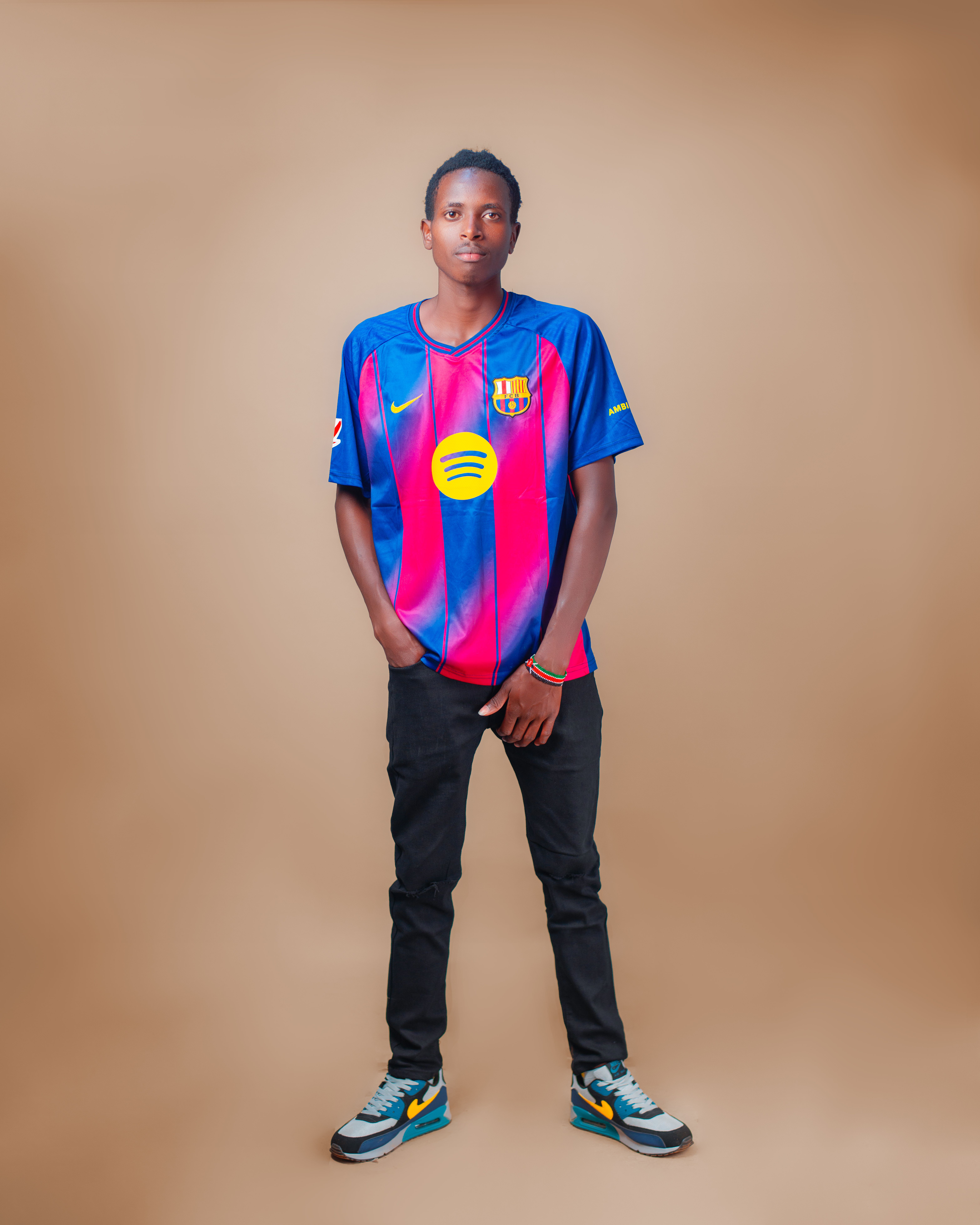 Portrait of a young man confidently posing in a vibrant football jersey against a plain background.