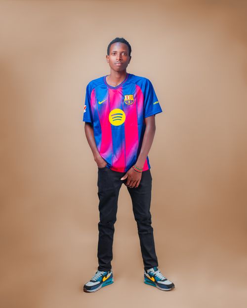 Free Portrait of a young man confidently posing in a vibrant football jersey against a plain background. Stock Photo