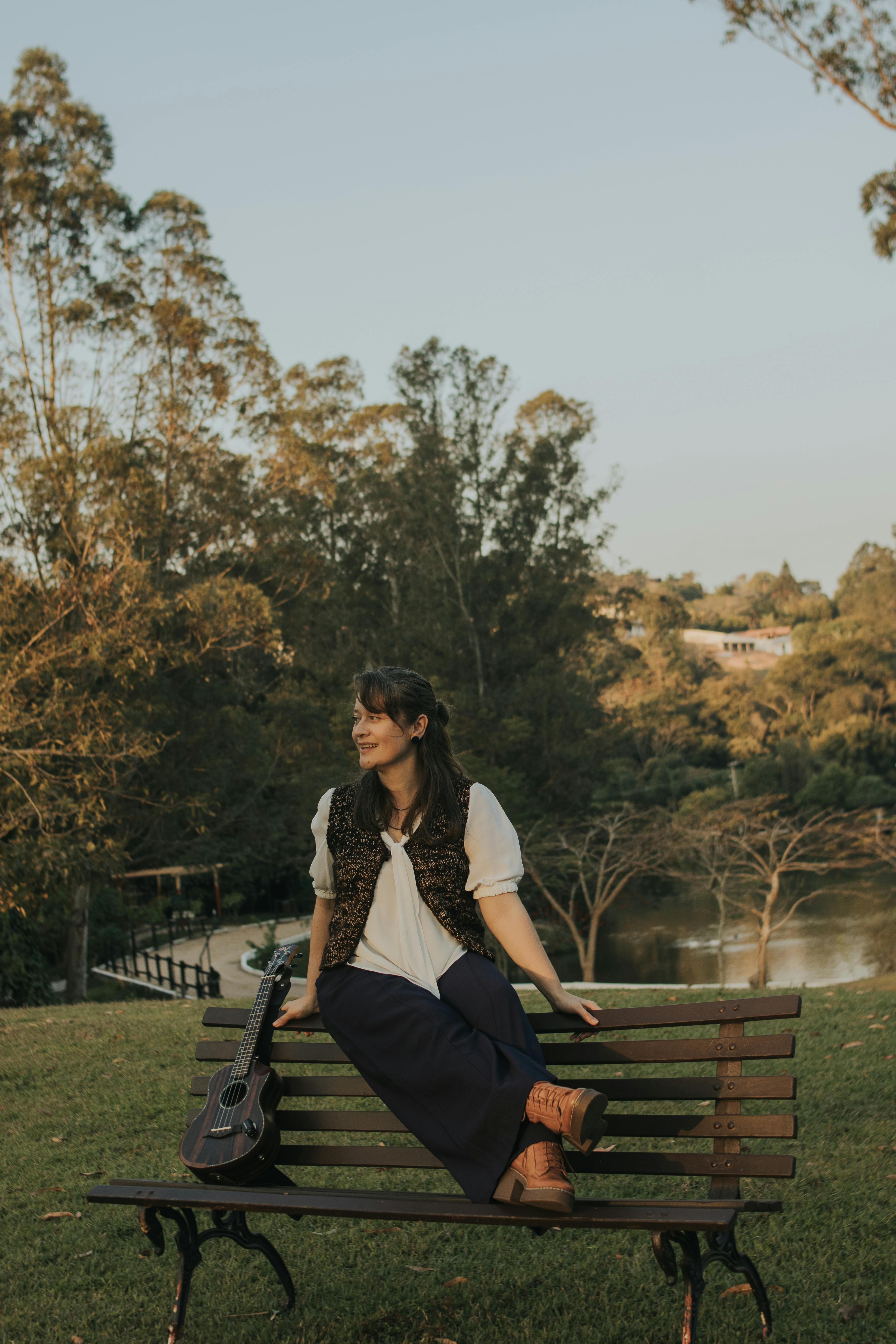 Woman enjoying a peaceful moment on a park bench with a guitar. Tranquil outdoor scene.