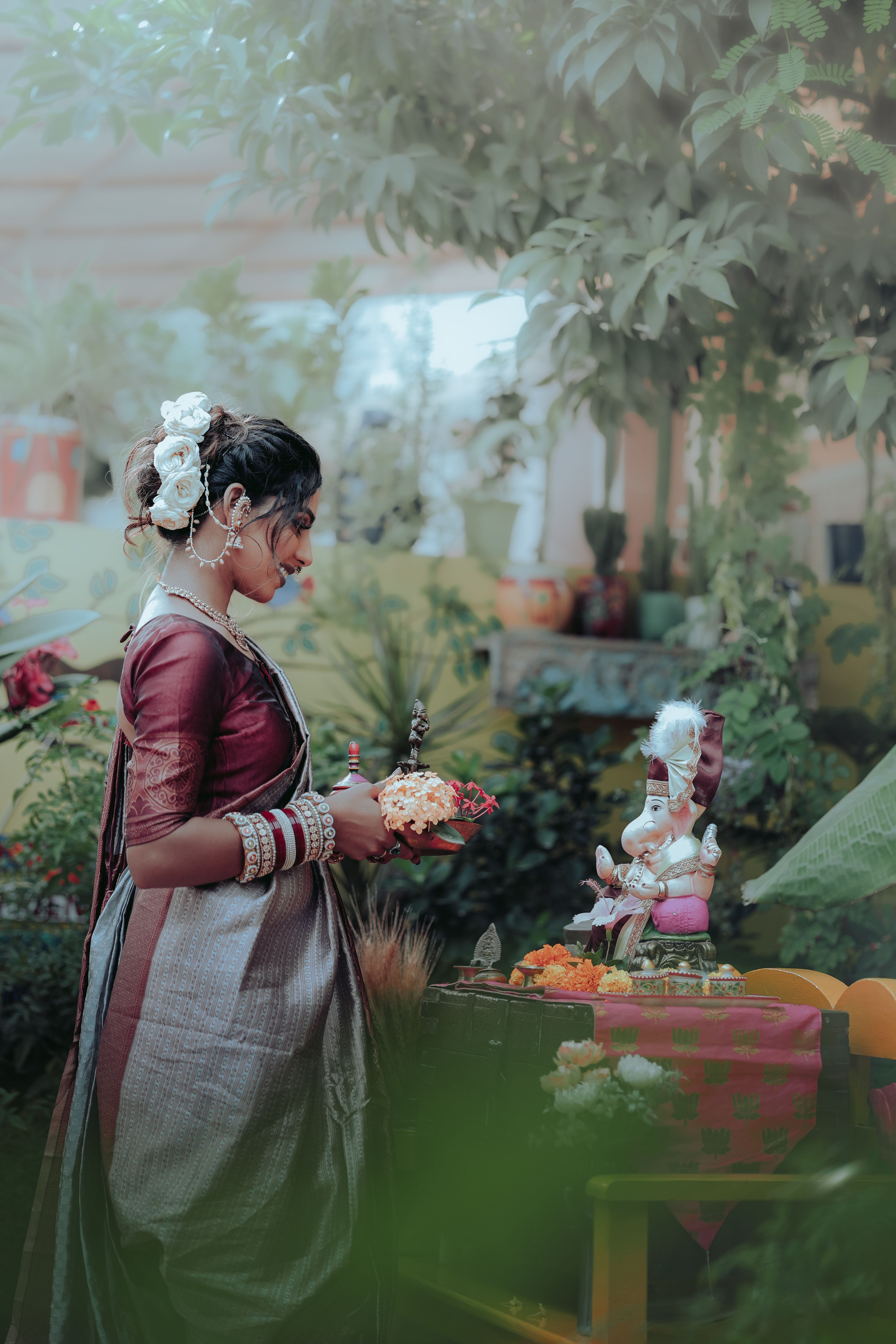 A woman performing a Hindu ritual in Mandvi, Gujarat under lush greenery, focusing on spiritual devotion.