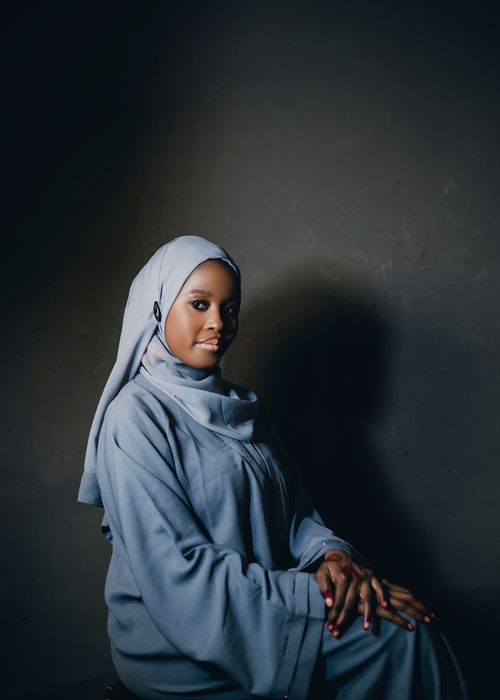 Free A serene portrait of a woman wearing a blue hijab, posing elegantly against a dark background. Stock Photo