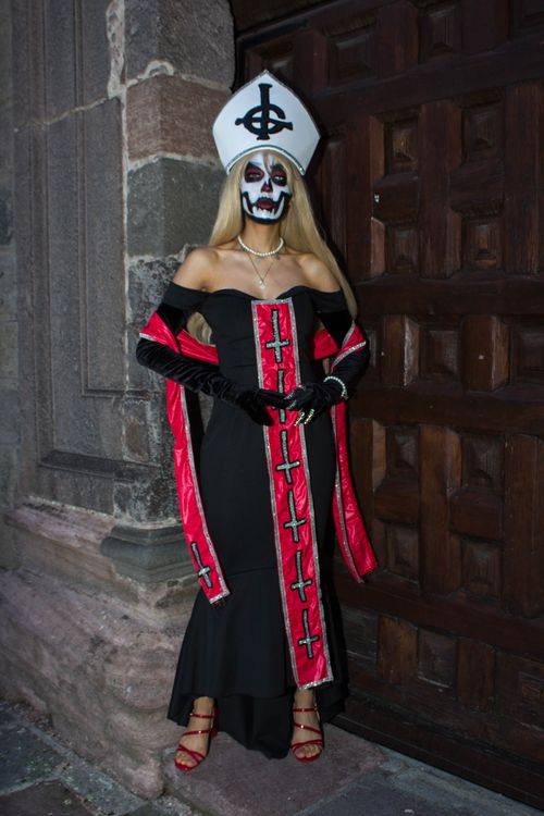 Free Woman in elaborate gothic costume with skull face paint in front of an ornate wooden door. Stock Photo