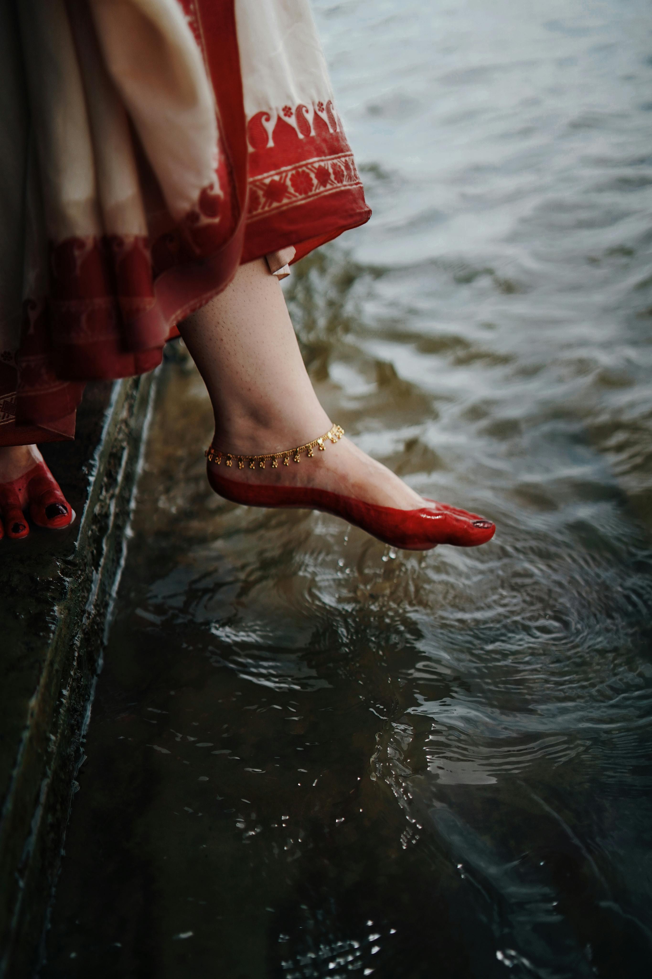 A woman in traditional attire touching the river water in Kolkata, India.